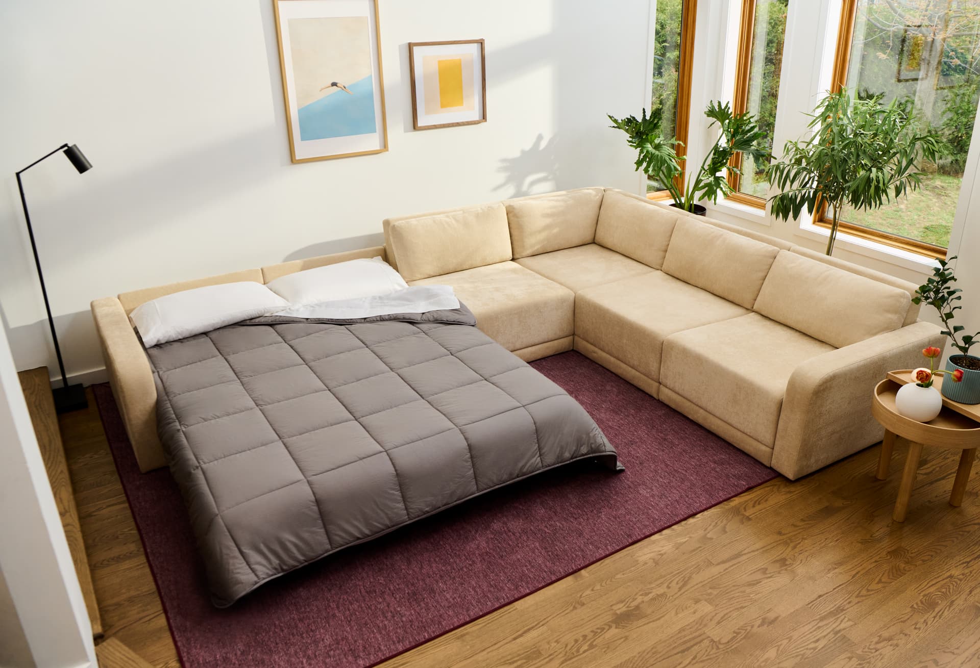 Orian sectional sofa bed opened into a bed with a grey comforter in a bright living room