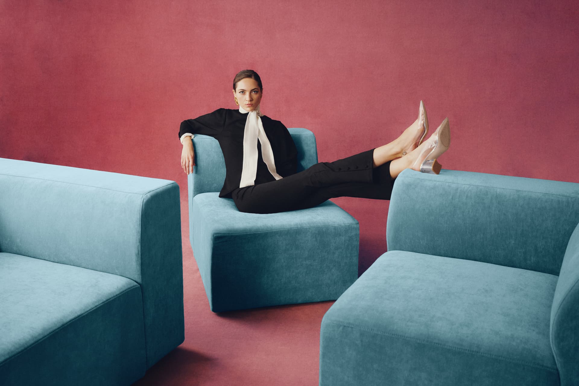 A woman reclining in one Cozey Atmosphere module with her feet up, between two other modules