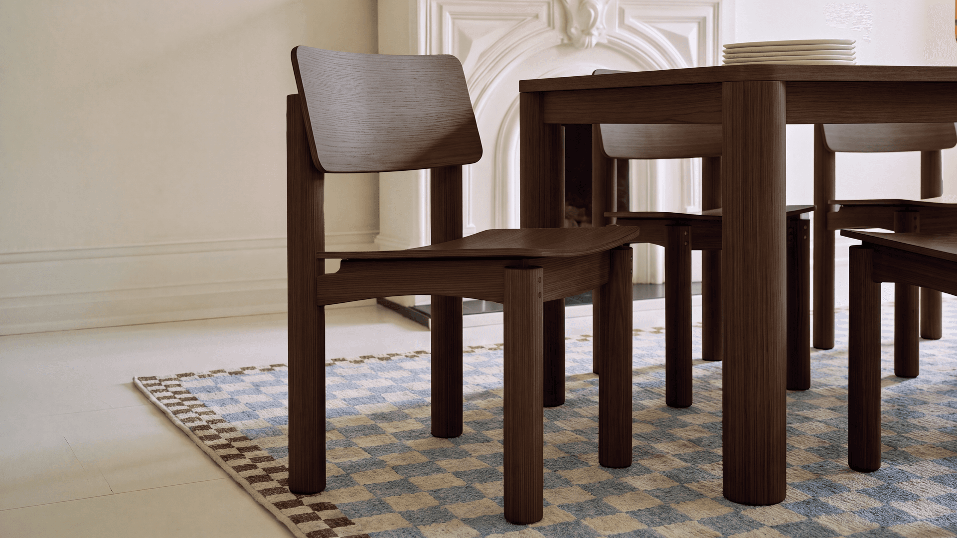 Walnut dining chairs and table on a checkered Cozey washable rug