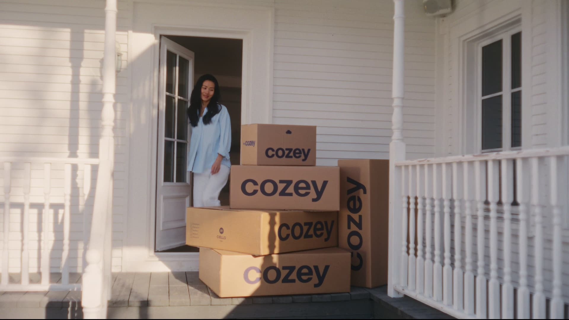 A woman opening her door to furniture delivery boxes