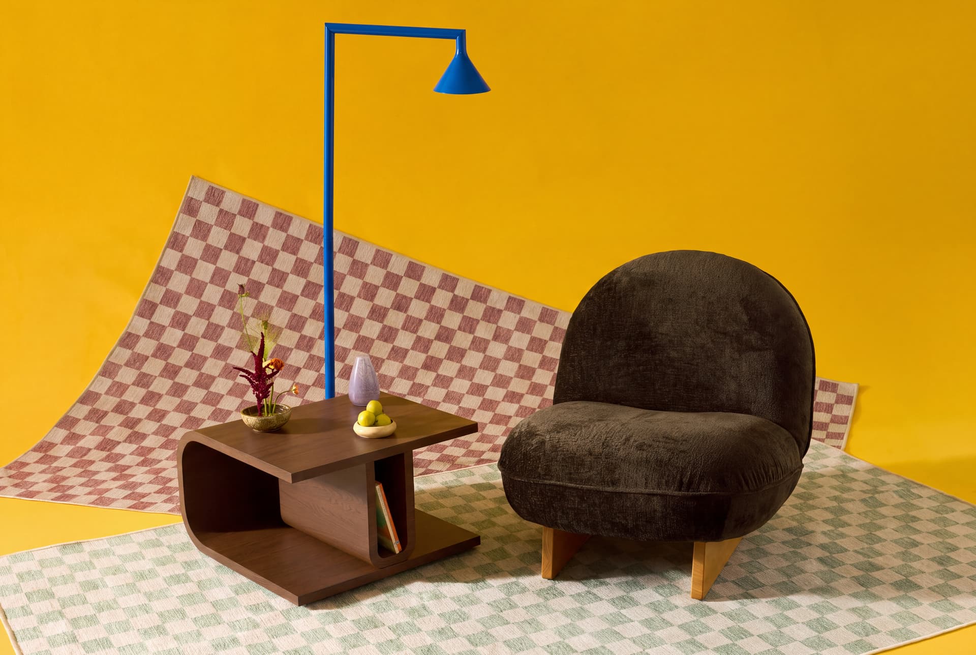 Cozey armchair and walnut side table on a checkered washable rug against a yellow backdrop